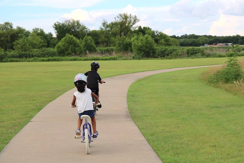 Two kids riding bikes on a path in a park in Suwanee