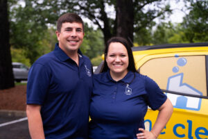 Home Clean Heroes owners in front of a vehicle smiling