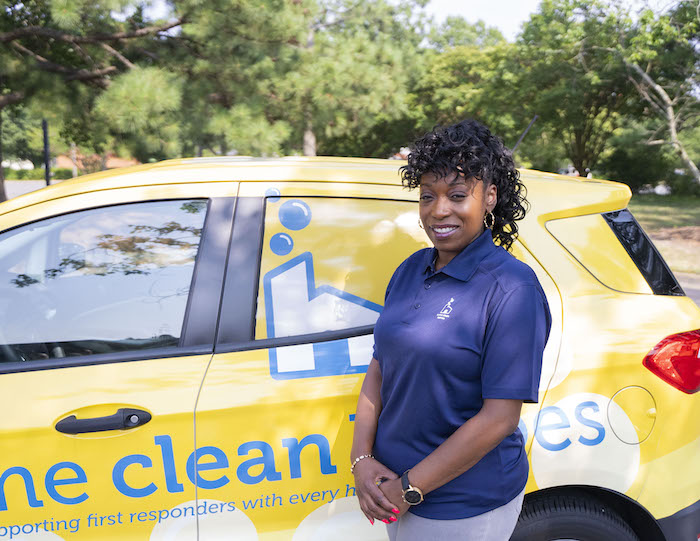 Home Clean Heroes office manager Michele smiling in front of Home Clean Heroes vehicle on a sunny day