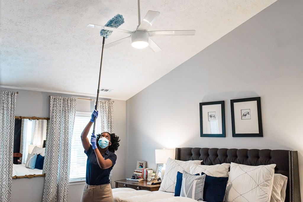 Cleaning technician dusting ceiling fan