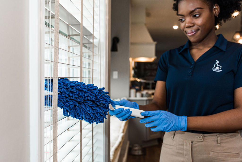 Cleaning specialist wiping blinds as part of house cleaning service with Home Clean Heroes