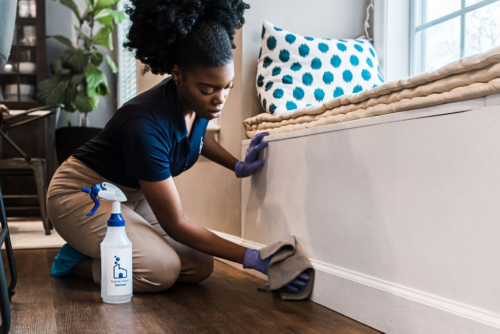 Cleaning technician wiping baseboards with microfiber towel