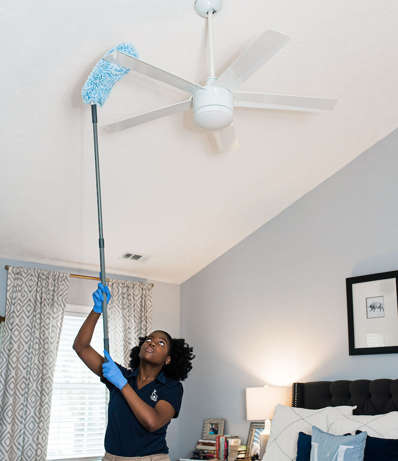 Home Clean Heroes cleaning technician dusting off fan blades