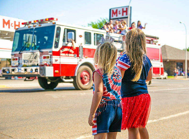 Two little girls looking at firemen on a firetruck