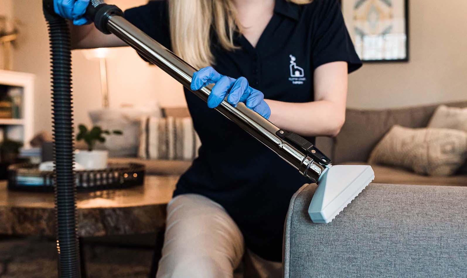 Cleaning technician vacuuming a couch arm