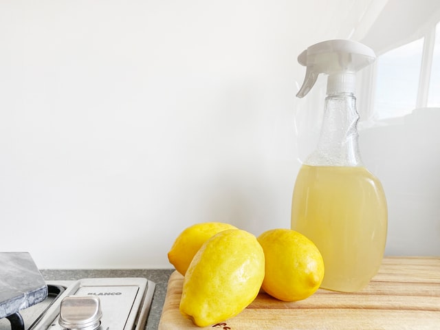Household cleaner next to lemons in kitchen