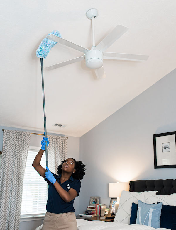 House cleaner dusting off ceiling fan blades
